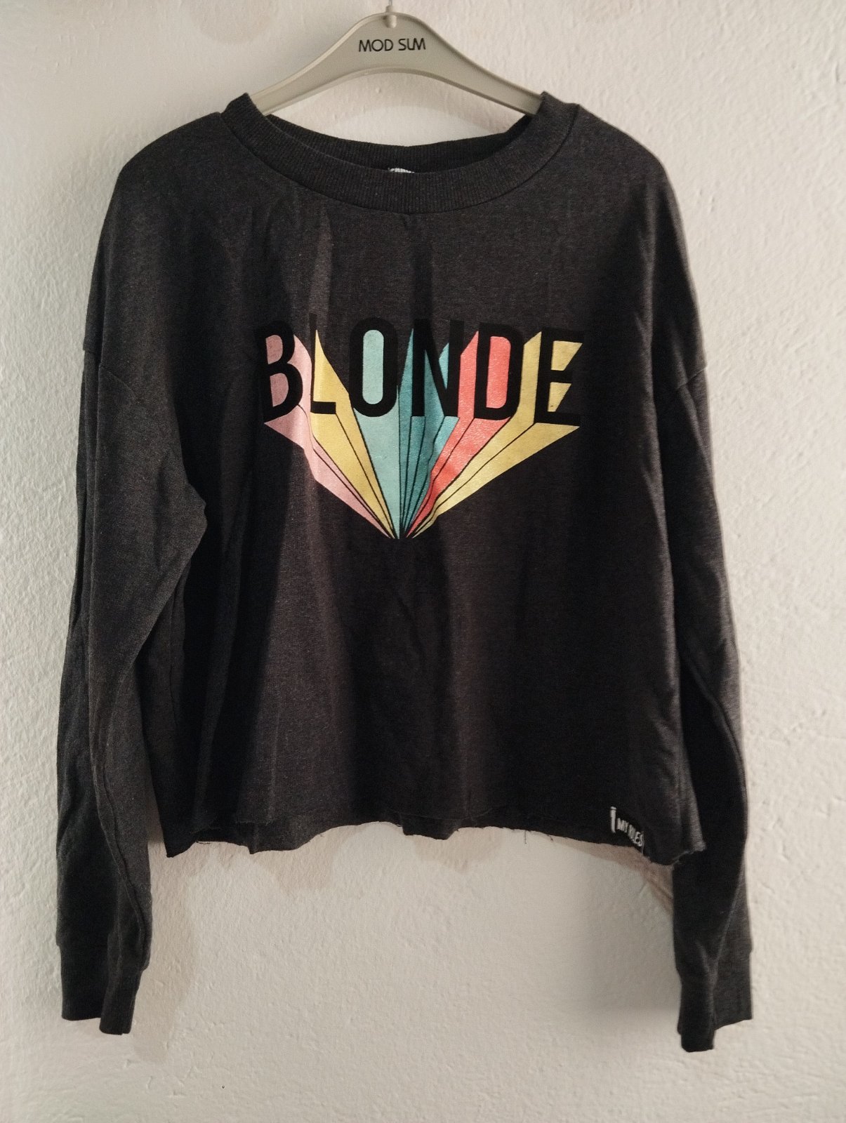 Haut gris foncé court de la marque Jennyfer présente le mot « BLONDE » surmonté d'un motif graphique coloré en forme d'éventail