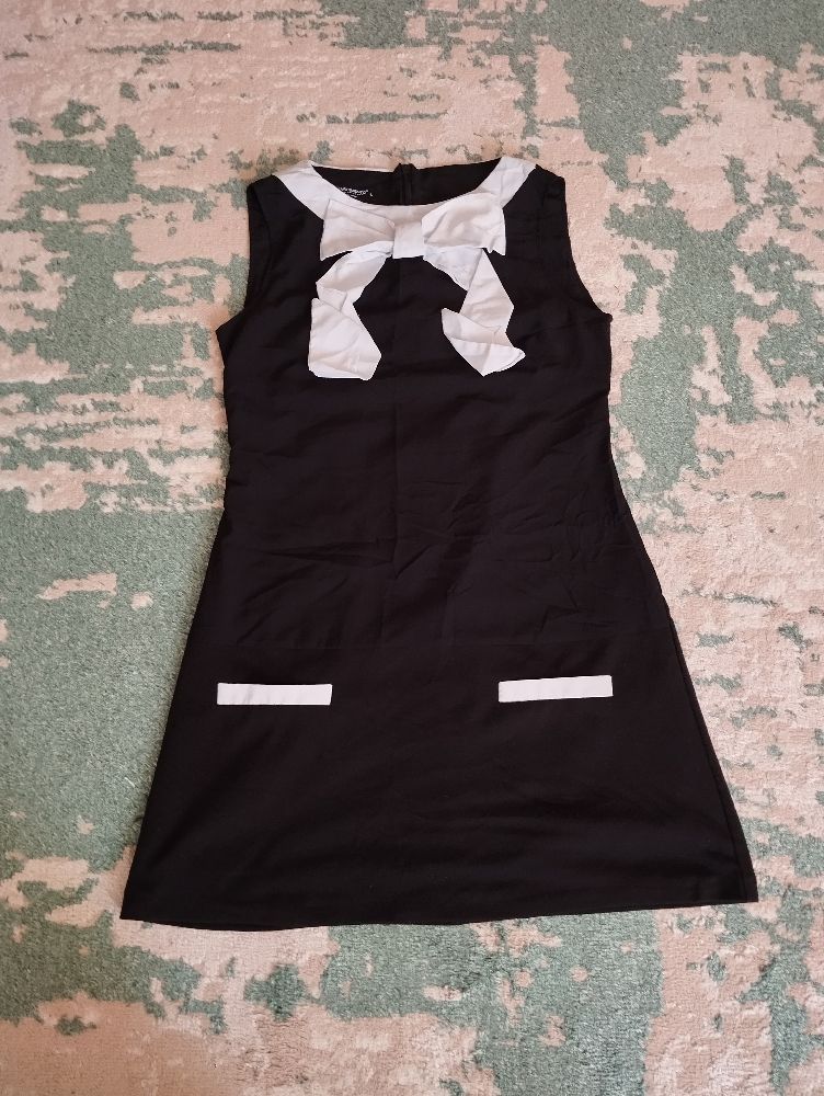 Mini-robe sans manches de couleur noir riche avec des nœuds blancs. 