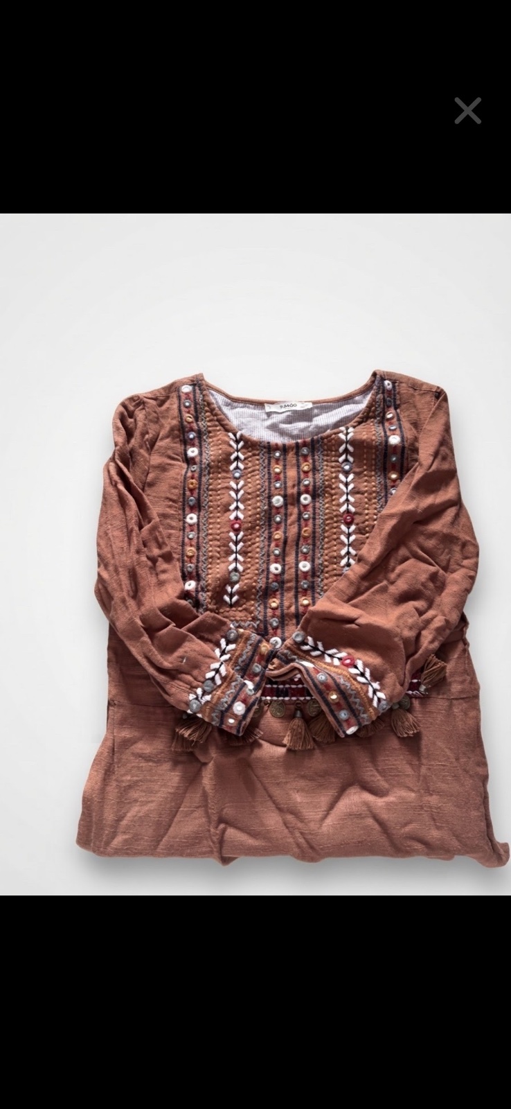 Une robe tunique Mango avec des broderies colorées et des détails à pompons sur le devant.