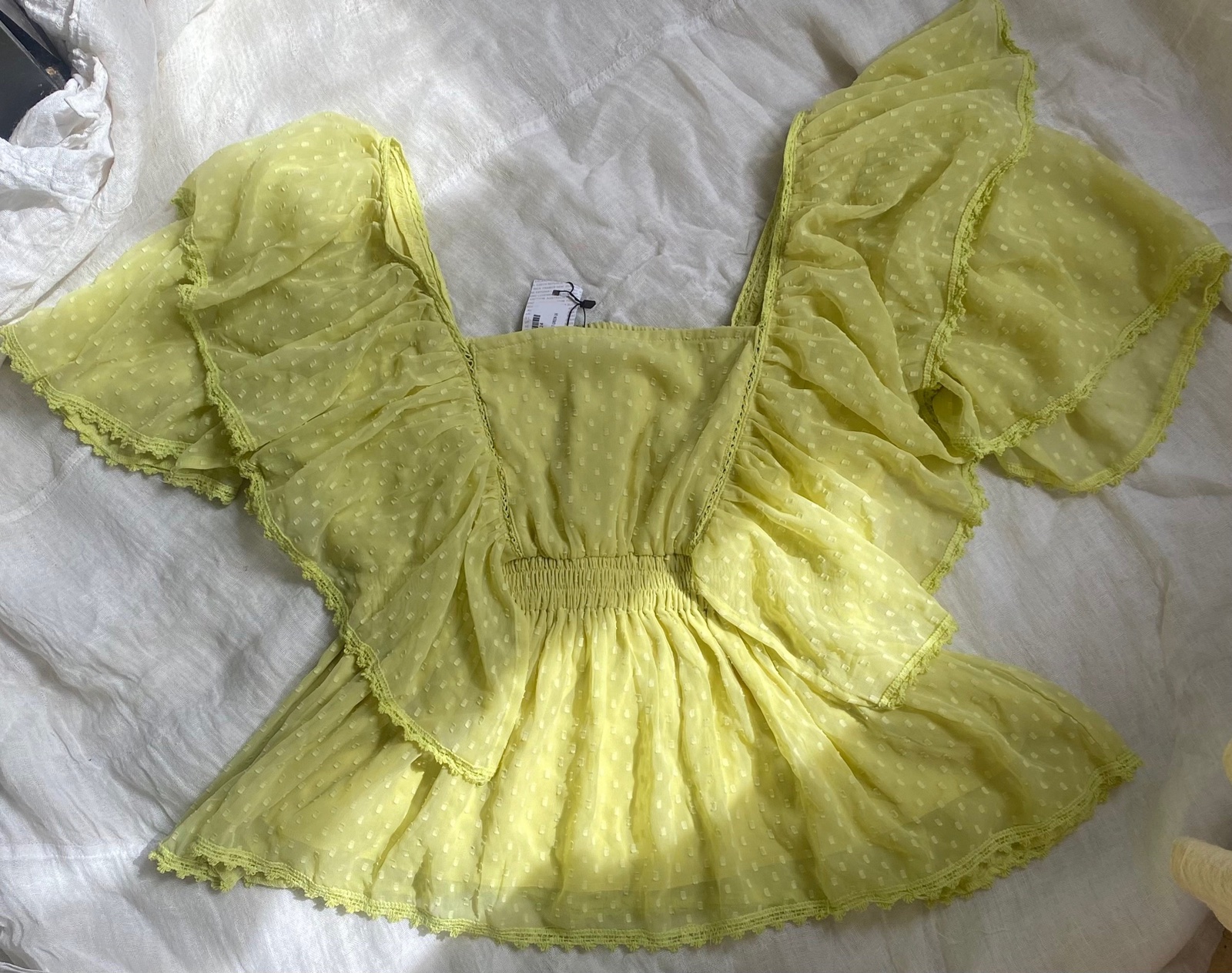 Un chemisier peplum jaune à smocks et volants avec un décolleté carré.