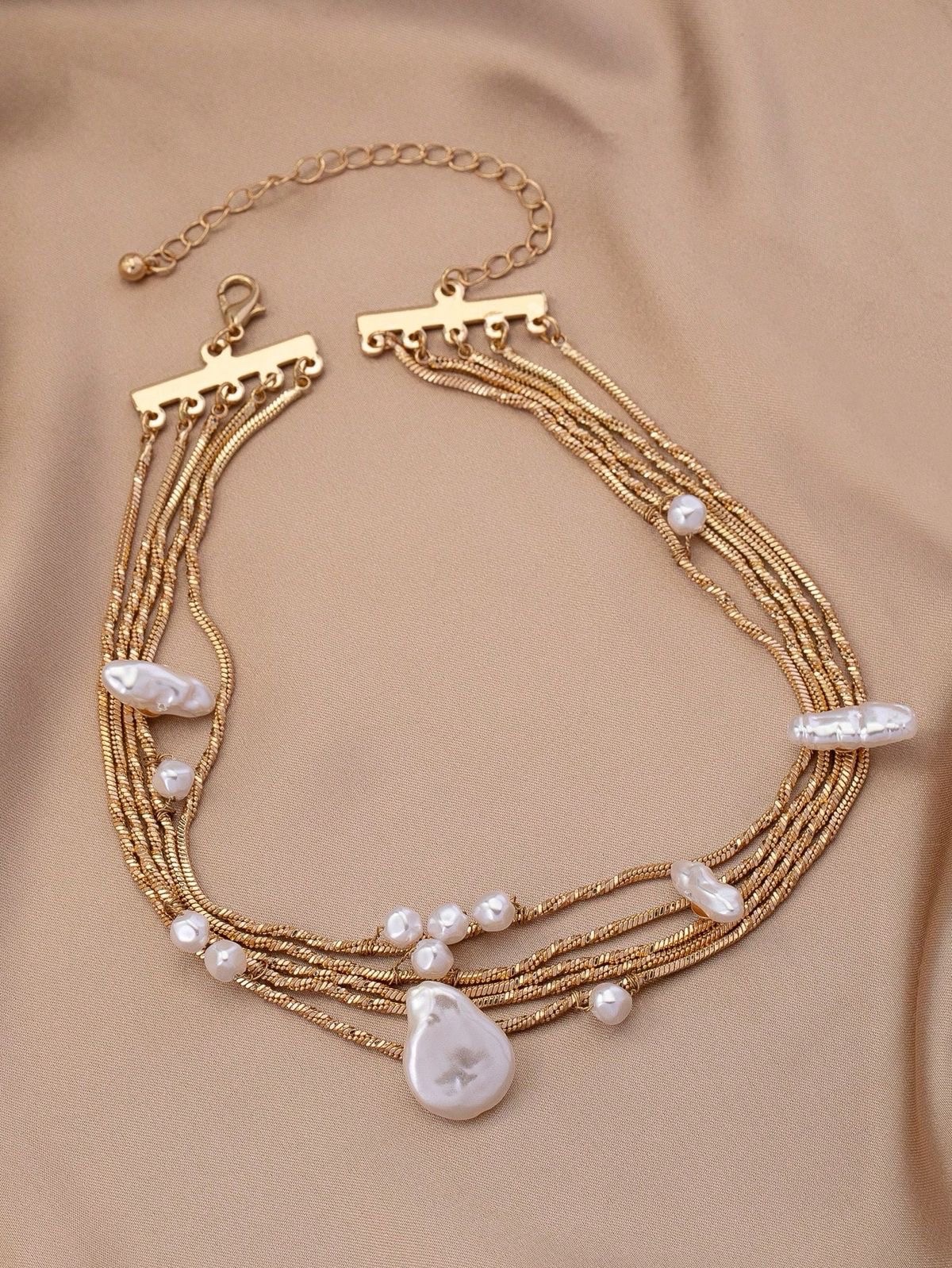 Ce collier de la marque SHEIN présente plusieurs rangées de chaînes dorées délicates ornées de perles baroques fantaisie
