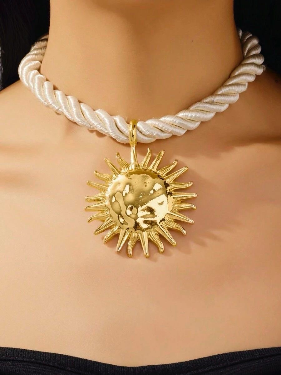 Ce collier est un modèle tendance de chez H&M, composé d'un cordon torsadé blanc et d'un grand pendentif en forme de soleil martelé