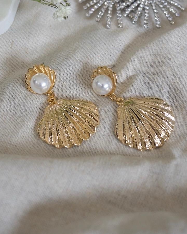 Ces boucles d'oreilles Sereday Collection arborent un design coquillage doré orné d'une perle