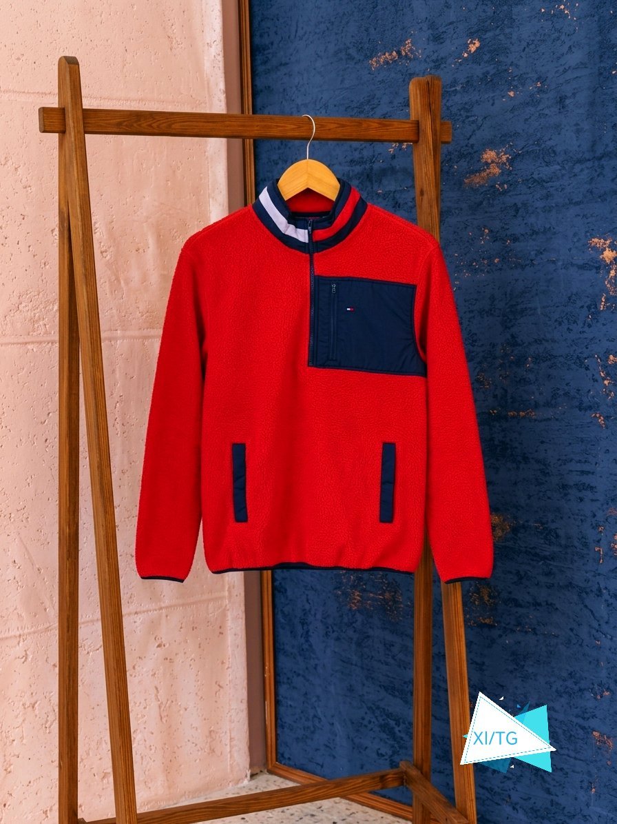 C'est une veste en polaire rouge de style rétro de la marque Tommy Jeans, dotée d'une poche zippée contrastée sur la poitrine et d'un col montant à quart de zip