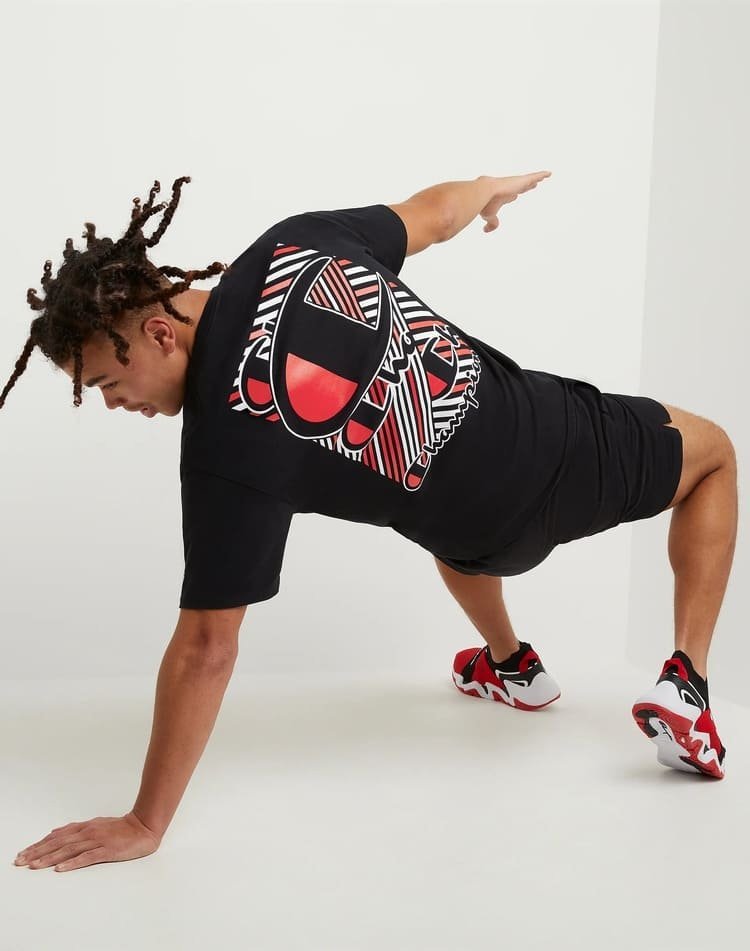 Ce t-shirt noir est un modèle graphique de la marque Champion arborant un grand logo imprimé rayé rouge et blanc dans le dos.