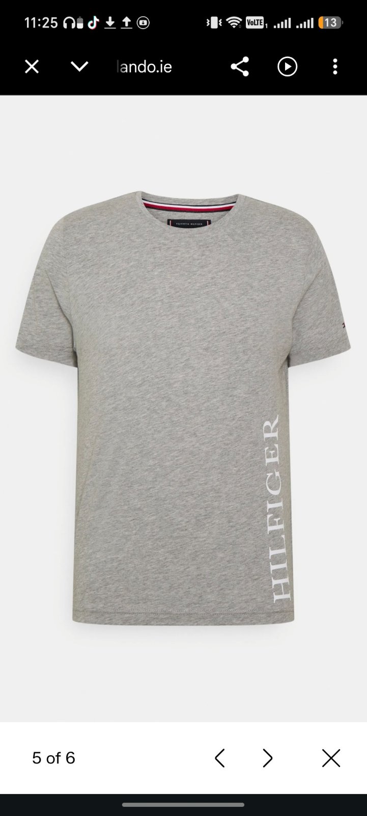 T-shirt gris Tommy Hilfiger présente un logo HILFIGER vertical audacieux le long du côté gauche.   