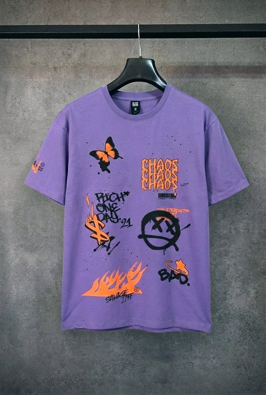 Ce t-shirt violet oversize présente des imprimés graphiques de style graffiti et street art, notamment un papillon orange, un smiley barré et des flammes.