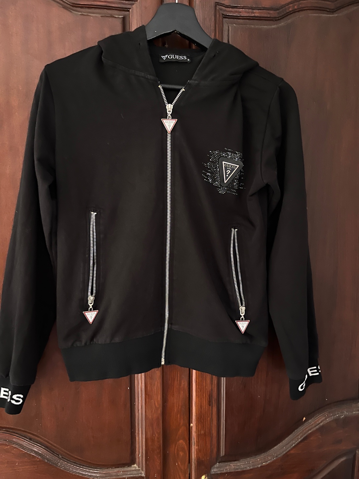 Black Guess zip-up hoodie featuring silver-toned hardware and distinctive triangular zipper pulls