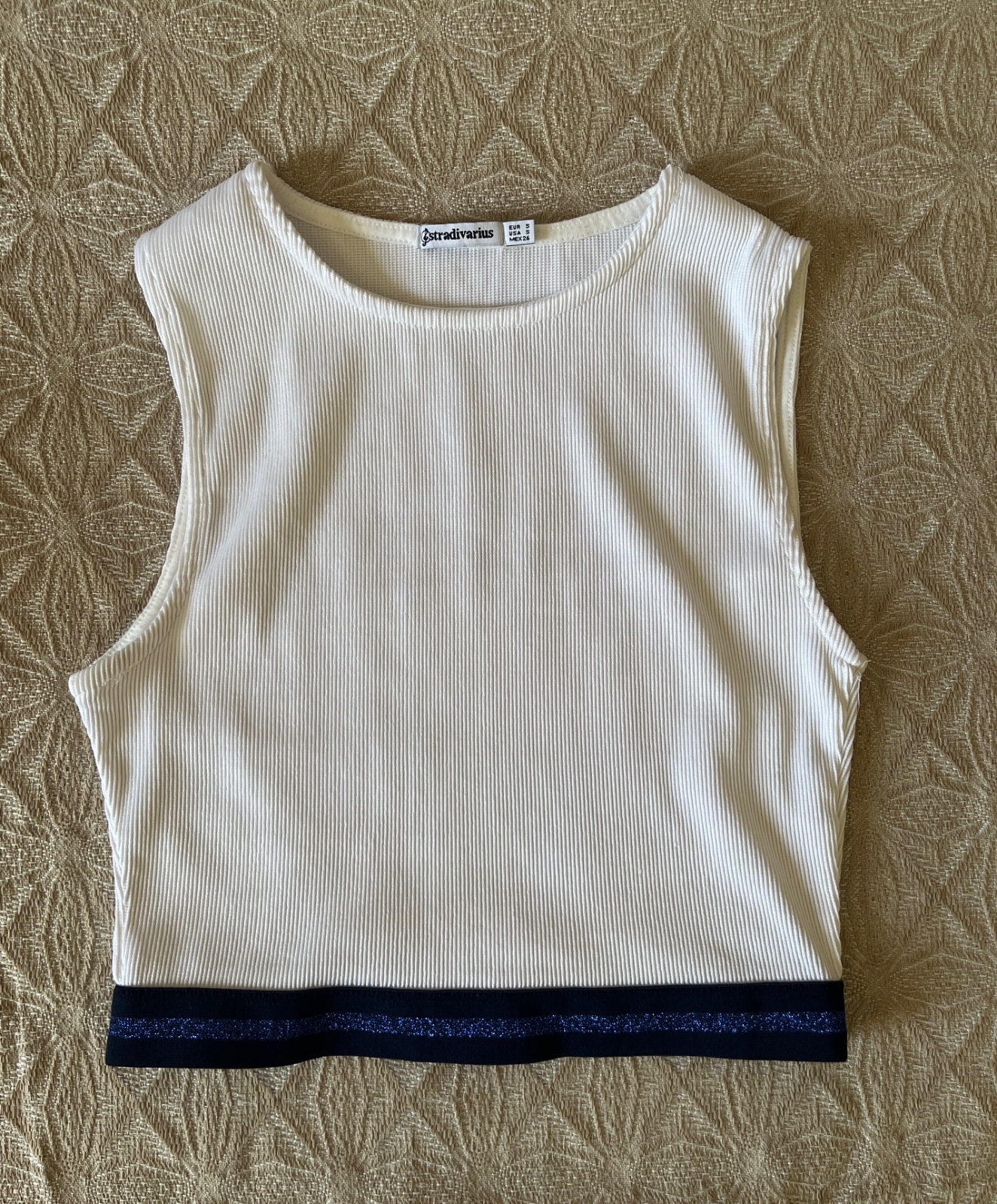 A white ribbed Stradivarius cropped tank top featuring a contrasting dark blue glittery hem band