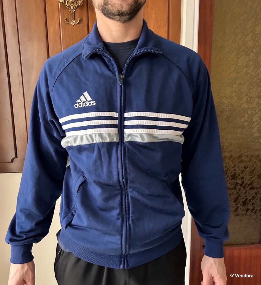 A vintage Adidas navy blue full-zip track jacket with white chest stripes and the embroidered Adidas logo