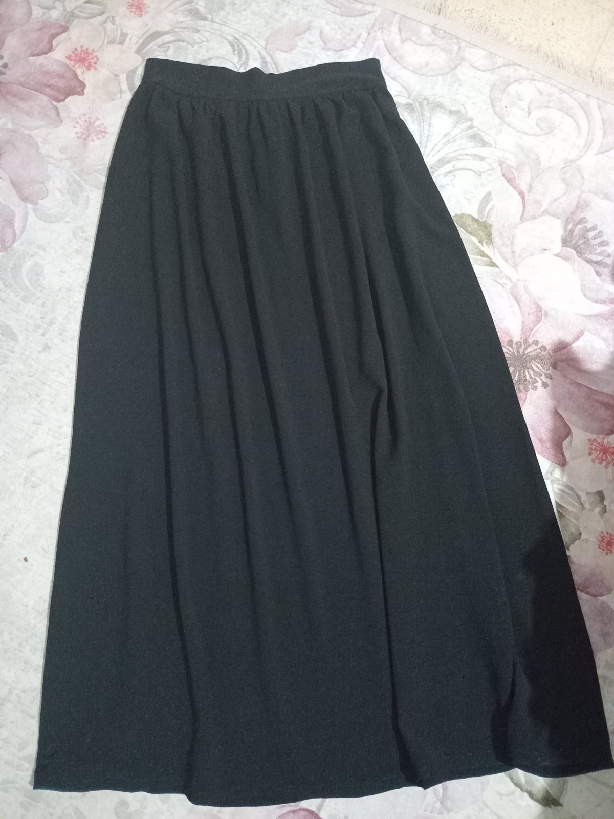  jupe longue noire fluide à taille haute présente une coupe évasée.