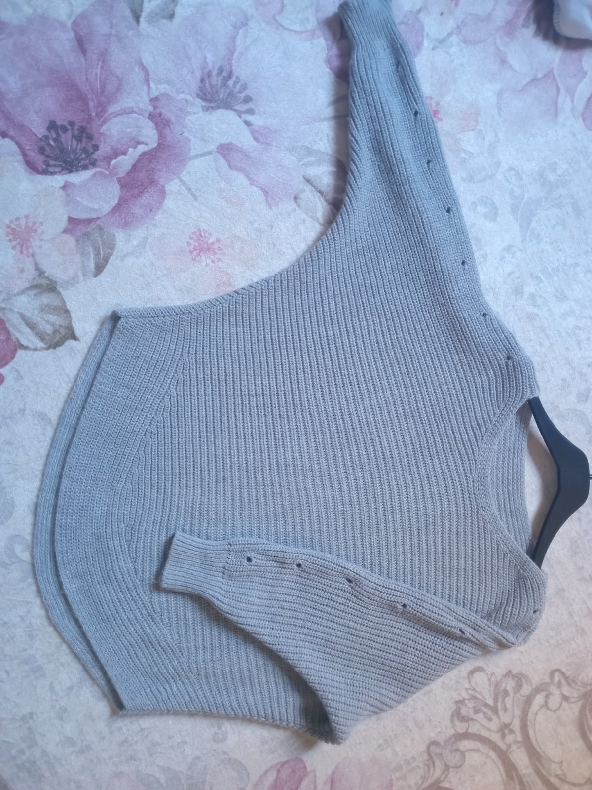 Pull en maille côtelée de couleur grise, caractérisé par une coupe asymétrique de style épaule dénudée