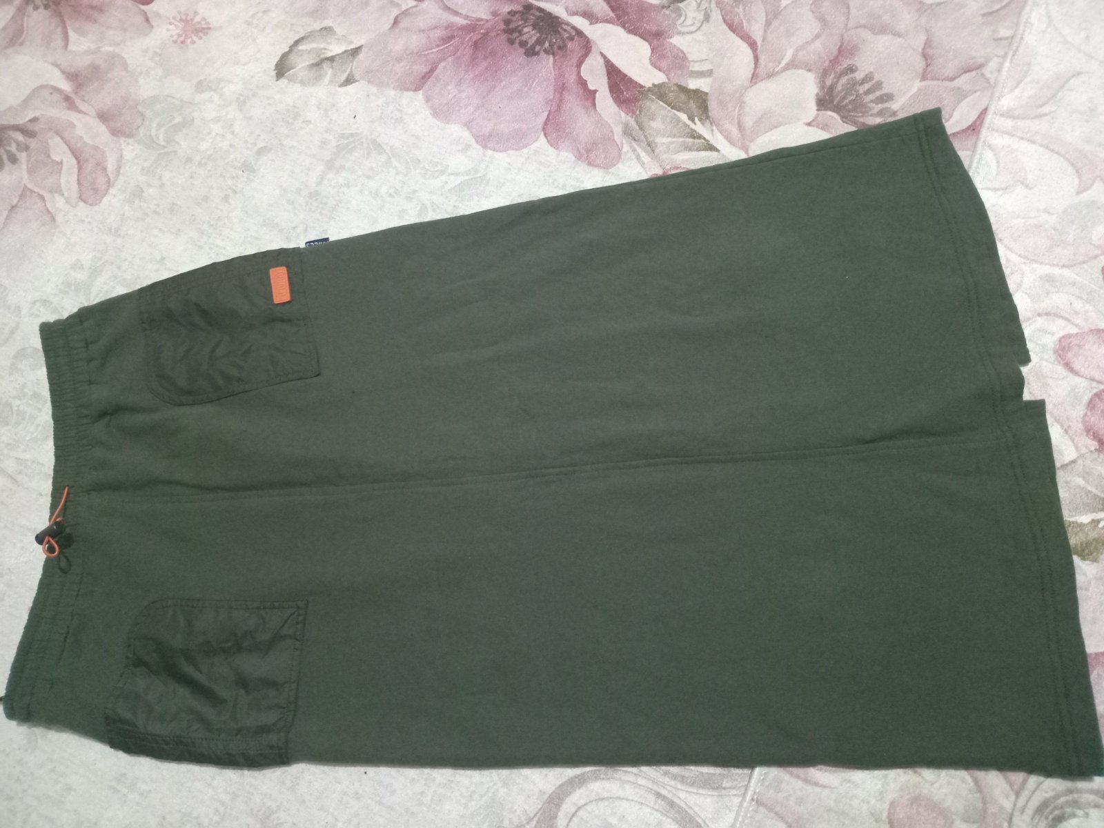  jupe mi-longue vert olive avec une taille élastique et des poches cargo. 