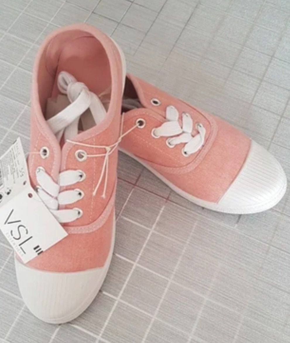 Une paire de tennis basses en toile coton rose avec des lacets blancs, un bout renforcé en caoutchouc 