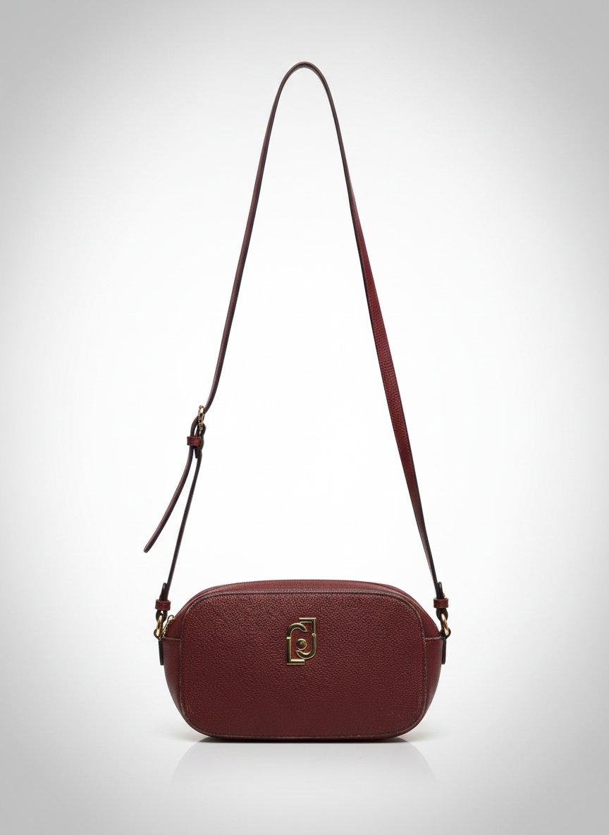 Ce sac à main est une pochette à bandoulière de la marque italienne Liu Jo, de couleur bordeaux (ou rouge brique foncé) mais les bords sont usés 