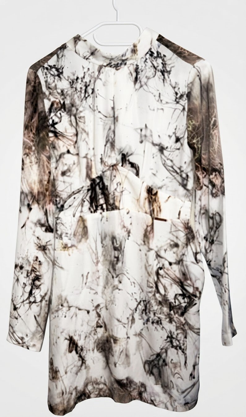 Robe courte à manches longues est un modèle de cocktail de la ligne Guess by Marciano, caractérisé par un col montant léger et un motif abstrait marbré noir et blanc.