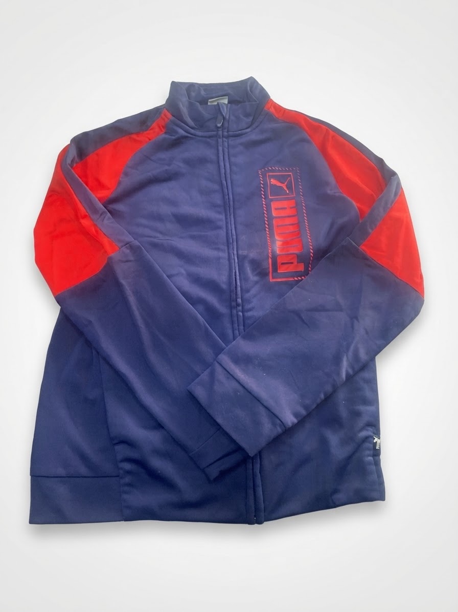 Veste de jogging zippée Puma pour enfant / adolescent, arborant un design color-block bleu marine et rouge avec un logo texturé vertical sur la poitrine.