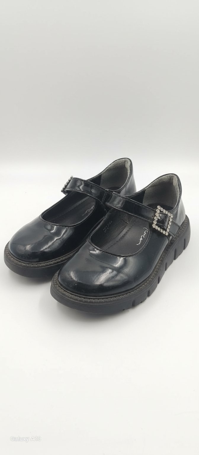 Une paire de chaussures pour fille de couleur noire brillante.