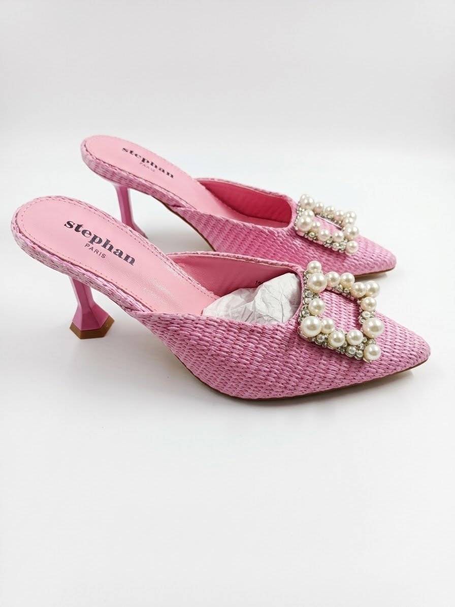Une paire d'escarpins mules roses à bout pointu ornés d'une grande boucle carrée décorée de perles et de strass