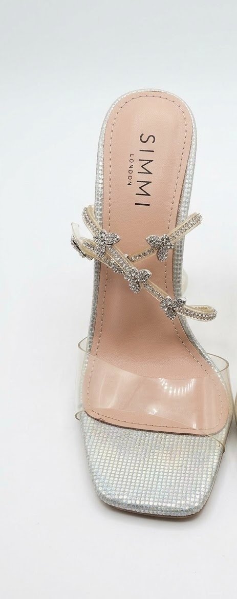 Mule plate texturé argenté avec bride en vinyle transparent et fines lanières de cheville croisées ornées de papillons en strass de la marque Simmi London importé France 