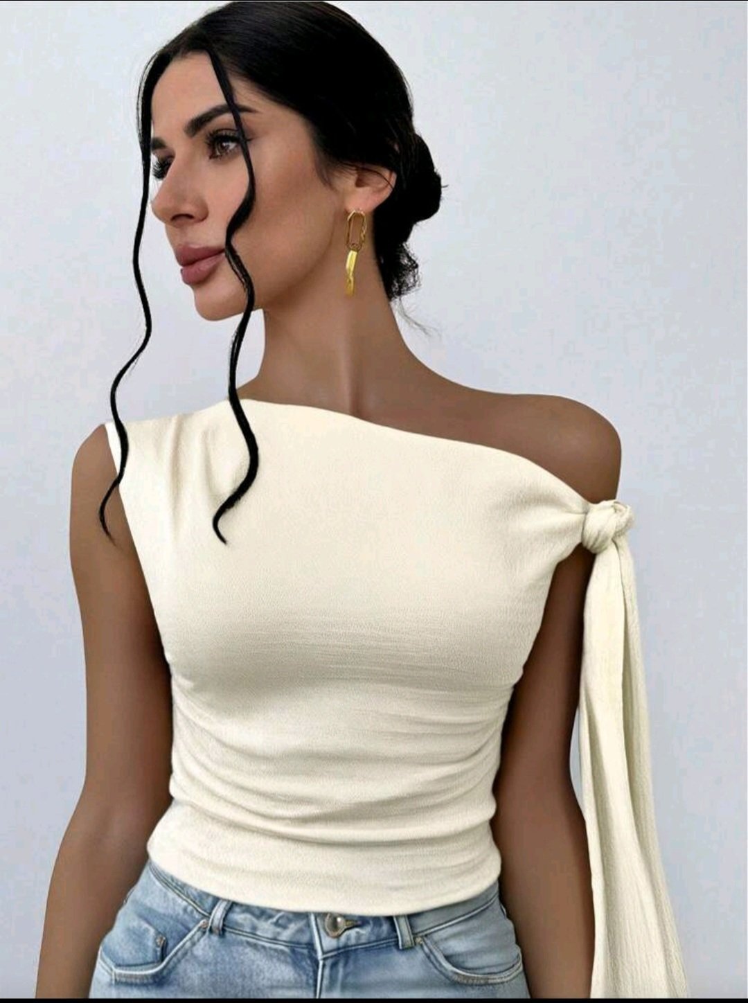 Un top féminin élégant et romantique à encolure asymétrique.