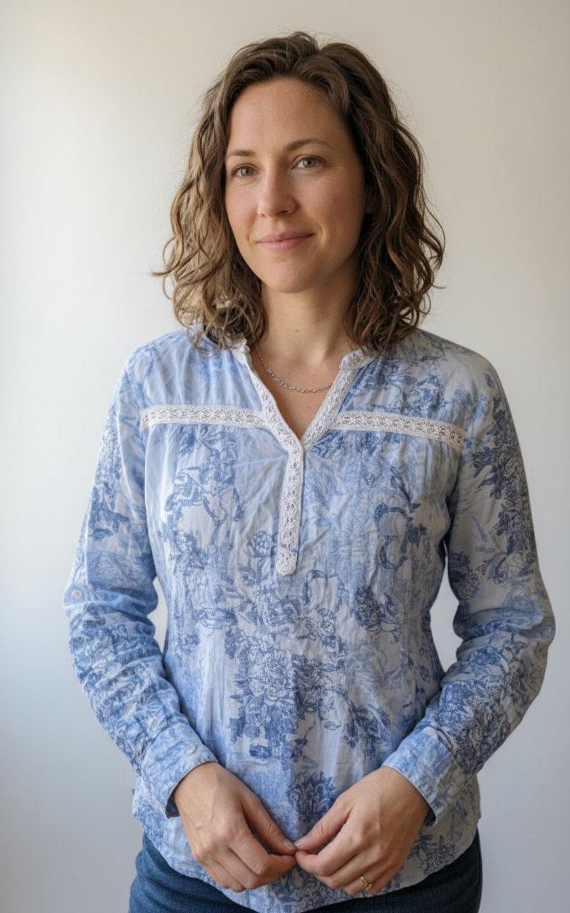  Une blouse bleue et blanche présente un motif floral délicat et des détails en dentelle au niveau de l'encolure