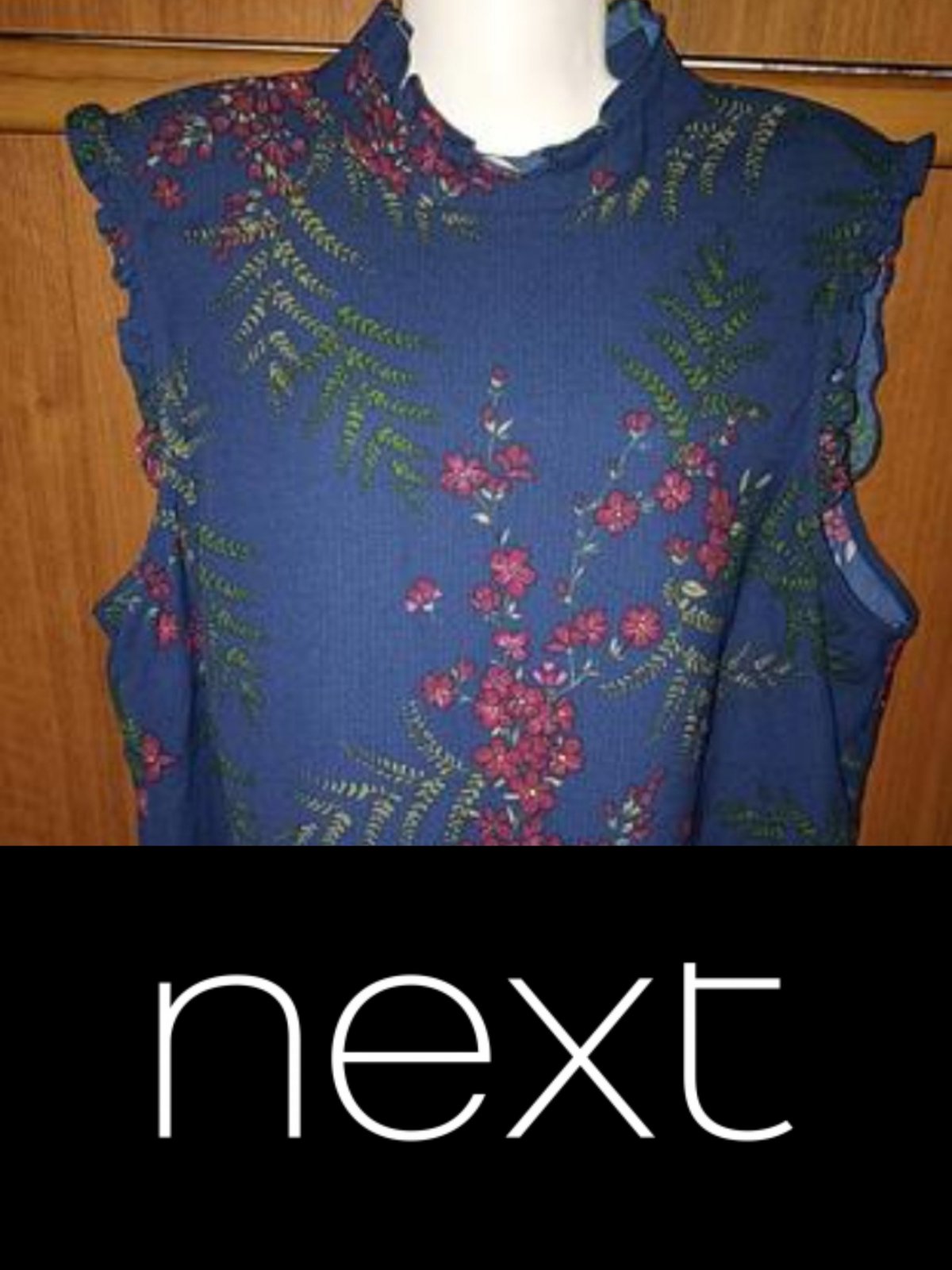 Chemise sans manches bleu marine à col montant et à volants, ornée d'un imprimé floral rouge et vert