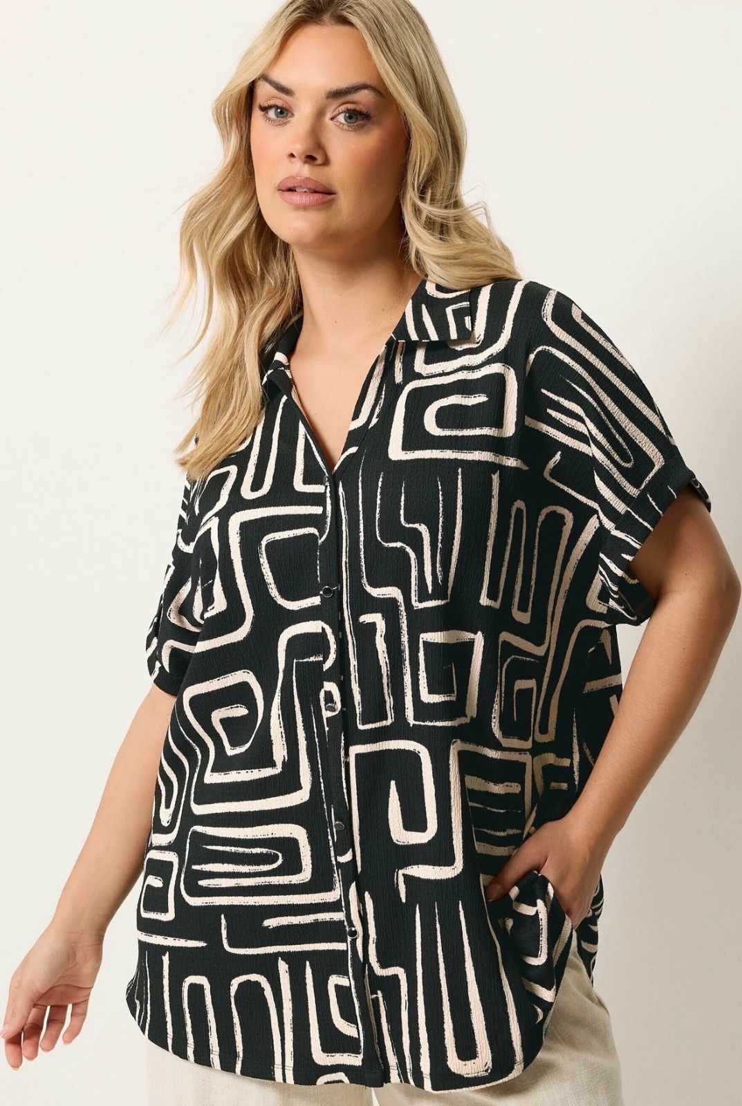 Chemise à manches courtes noire et blanche se distinguant par son motif géométrique abstrait.