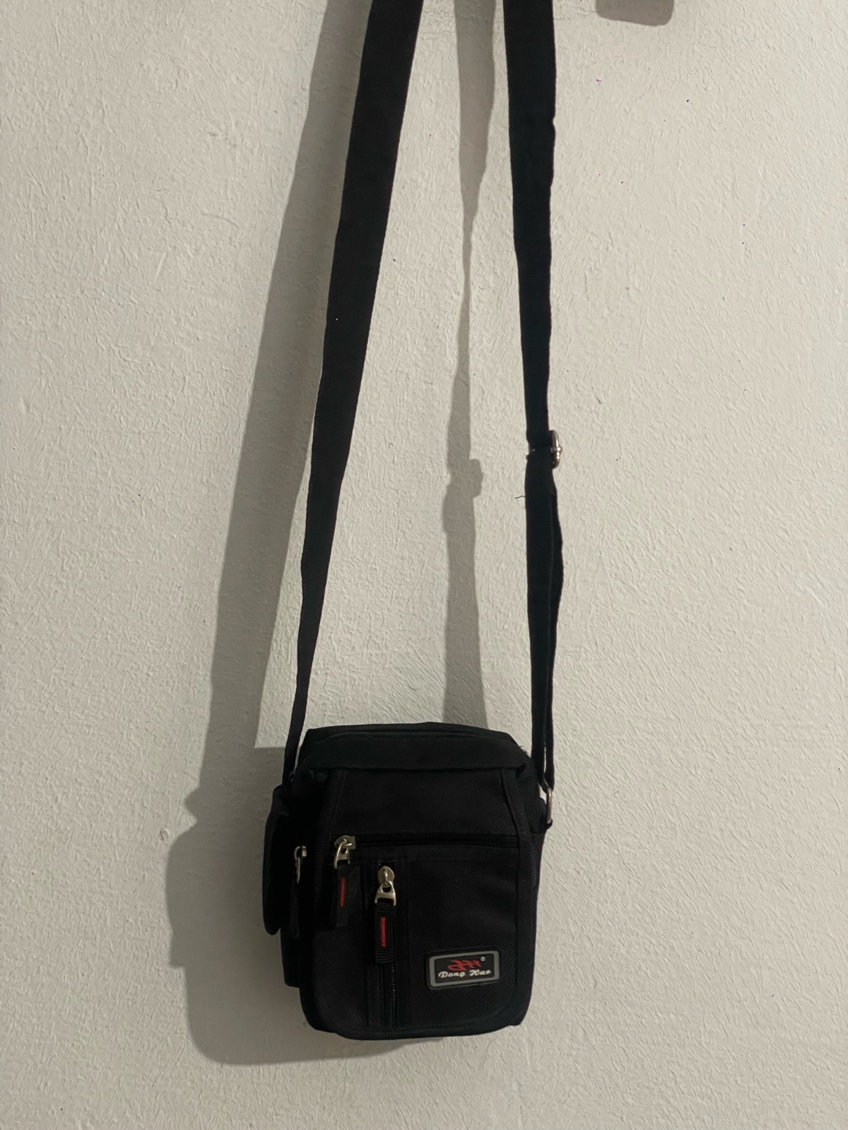 Une petite sacoche bandoulière noir marque Dong Hao 