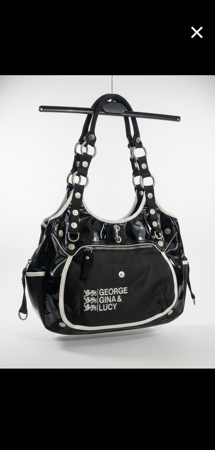 Un sac à main George Gina & Lucy, potentiellement le modèle "Zona Caliente", en cuir verni noir avec des détails blancs.