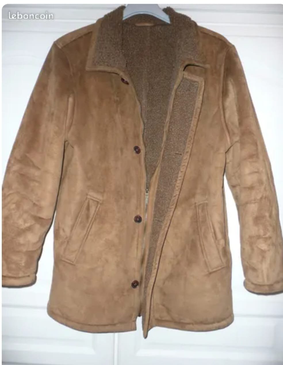 La veste illustrée est une veste de style "peau lainée" ou en daim synthétique, de couleur marron clair ou camel.