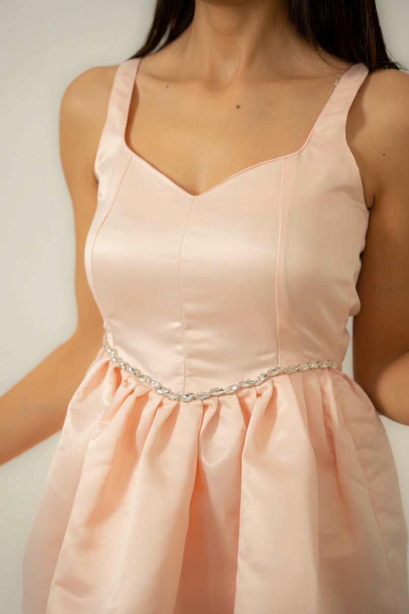 Une robe rose saumon ornée de strass sur le devant.