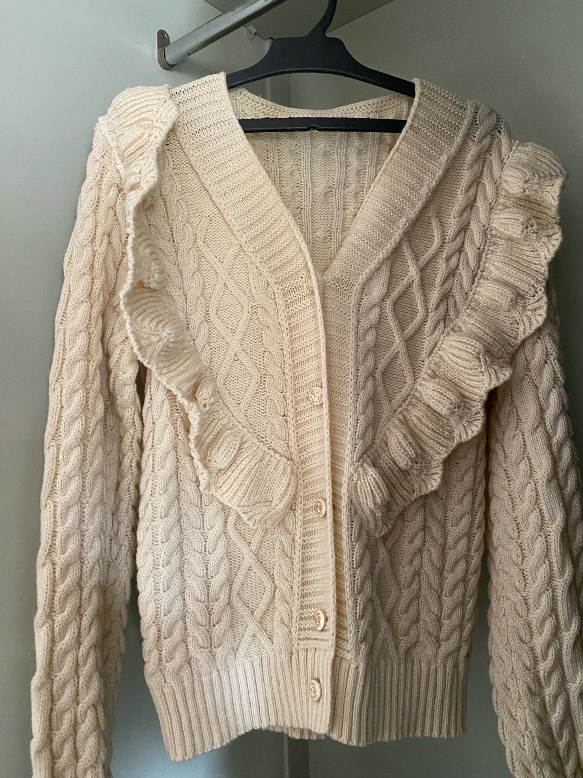 Ce cardigan en maille de couleur crème/beige clair présente un style élégant et féminin