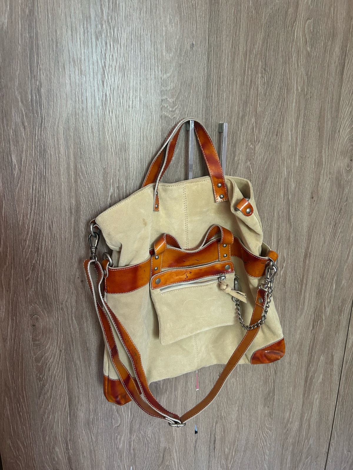 Ce sac cabas Estellon en daim beige présente des finitions en cuir verni orange et une chaîne décorative.