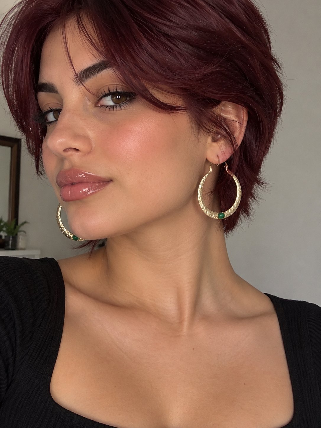 Boucles d'oreilles ayant la forme  des créoles texturées martelées de couleur dorée avec une pierre ovale de couleur verte.