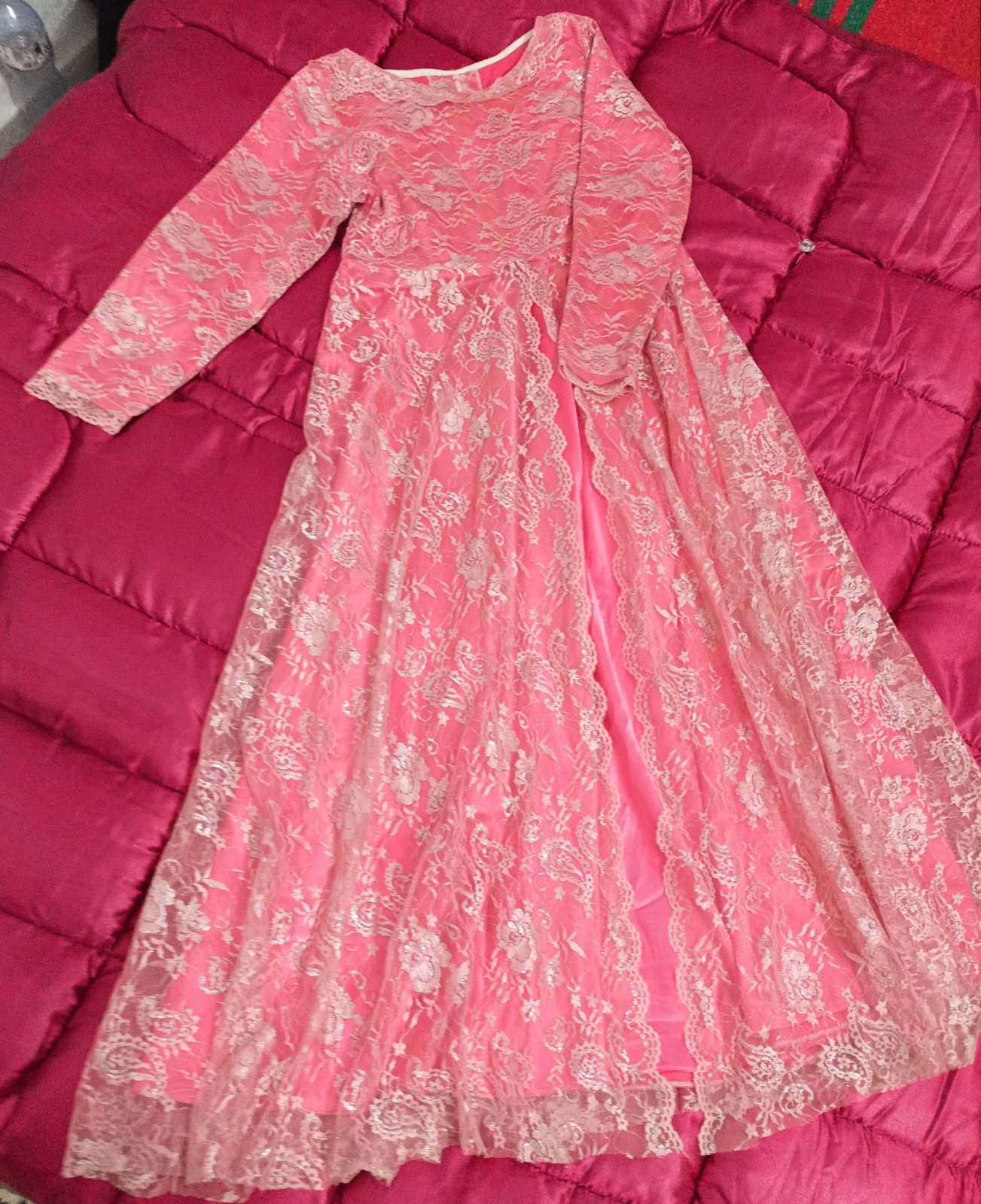 C'est une robe longue en dentelle rose avec des manches longues.
