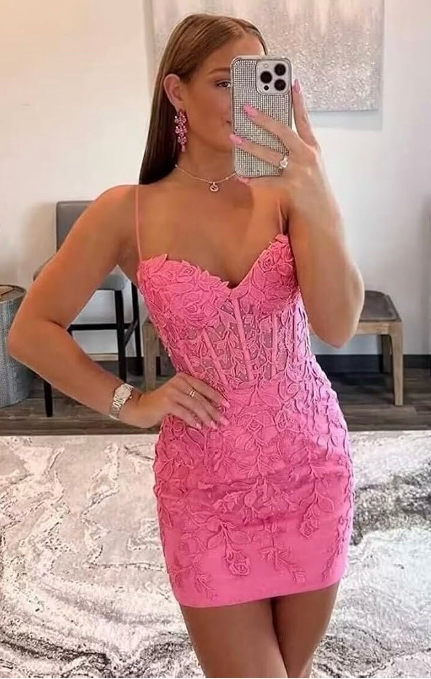 Mini-robe moulante rose vif se distingue par son corset structuré à bretelles spaghetti et ses délicates appliques florales en dentelle 3D.