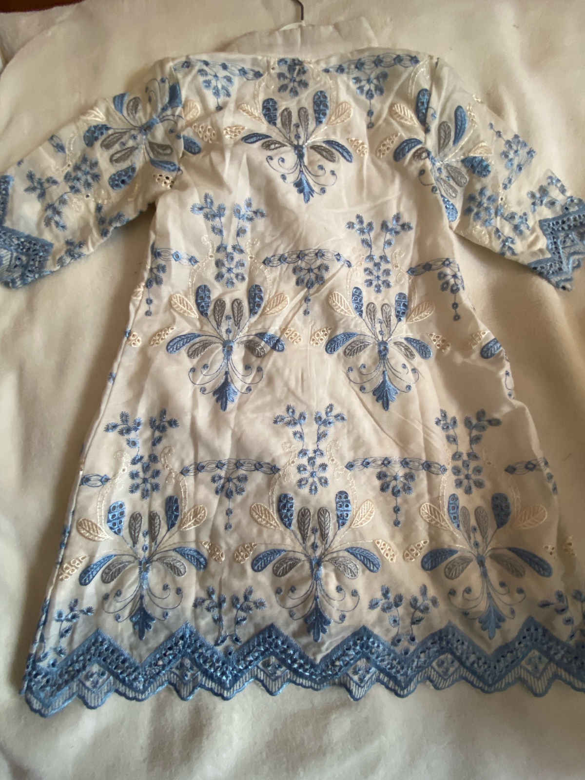 Une robe pour enfant blanche avec des broderies bleues,