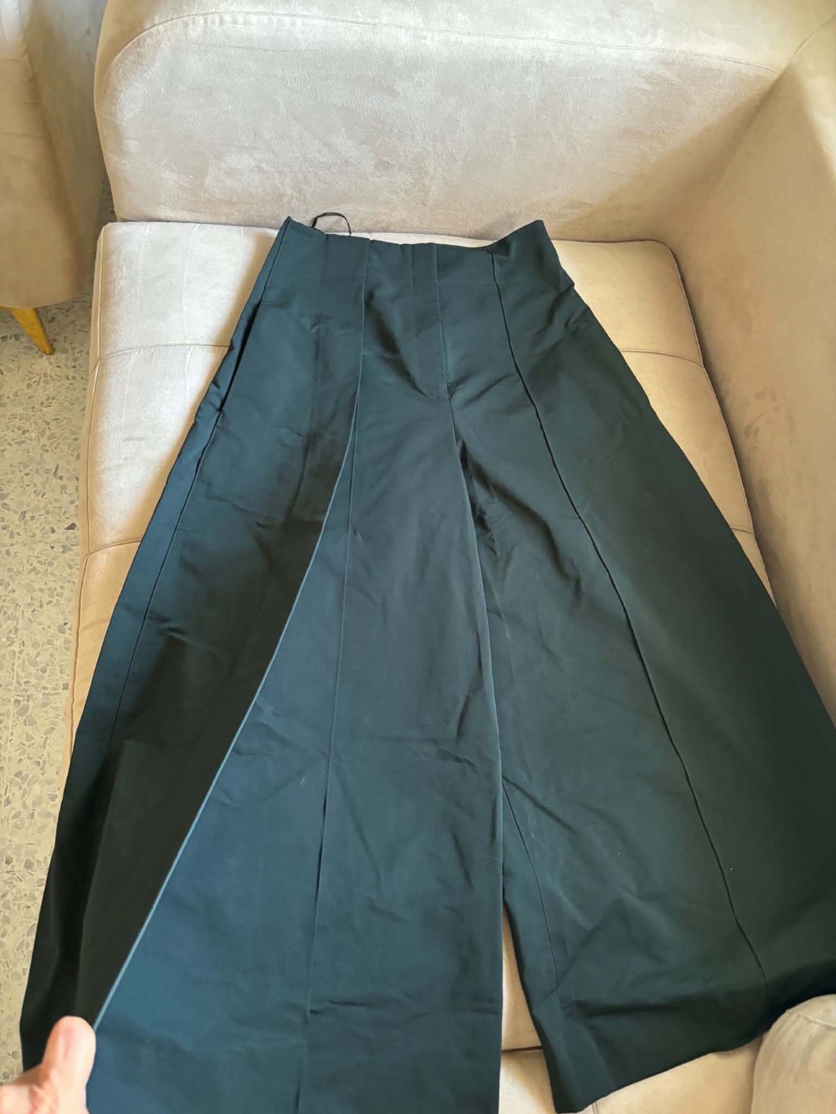 Pontalon large vert fone taille haute qui presente un plis frontale marques et des coutures apparentes
