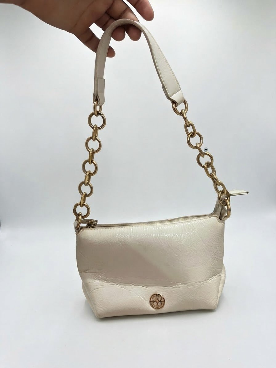  Sac à main blanc cassé présente une bandoulière mixte en cuir et gros maillons dorés ainsi qu'un discret logo circulaire sur le devant