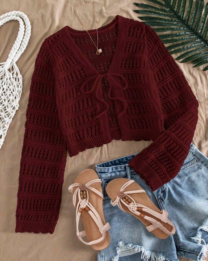 Cardigan bordeaux en maille ajourée à nouer sur le devant, associé à un short en jean déchiré et des sandales plates à brides