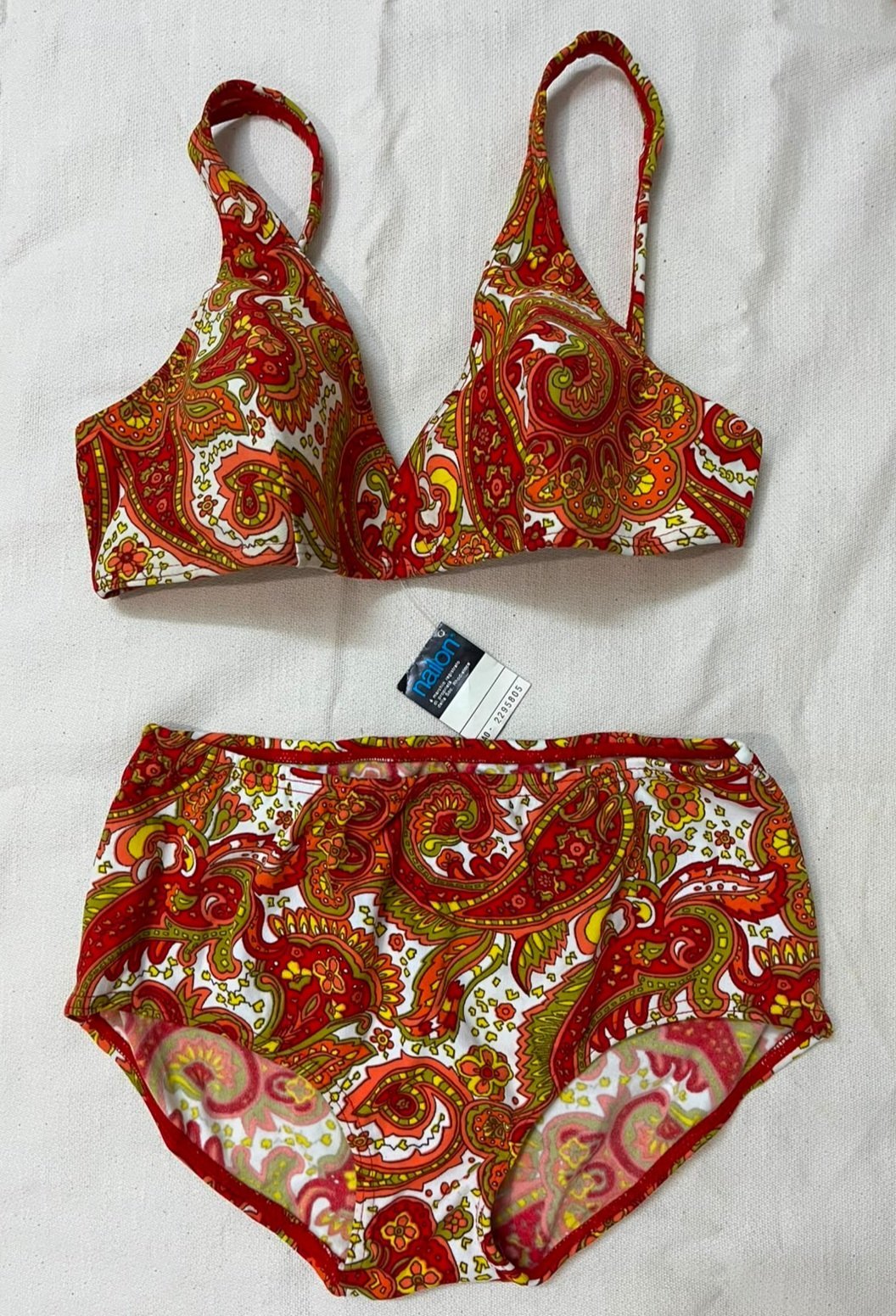 Maillot de bain deux pièces est un ensemble de la marque Nallon arborant un motif cachemire vibrant aux tons rouges, oranges et jaunes