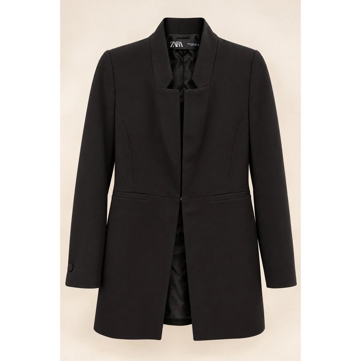 Veste longue noire Zara (également connue sous le nom de levita ou blazer long à revers inversés), caractérisée par son col particulier, sa coupe cintrée et sa fermeture à crochet métallique sur le devant