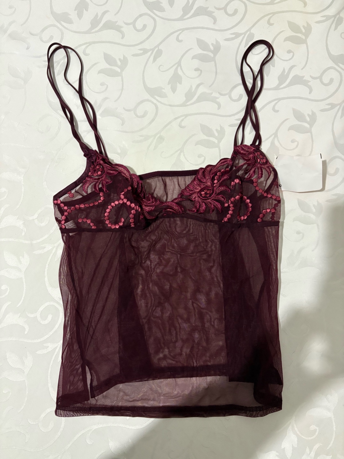 Joli top lingerie bordeaux, neuf avec étiquette. Un modèle féminin et élégant qui apporte une touche de glamour à toutes vos tenues. Léger, confortable et facile à porter, il se marie aussi bien avec un jean qu’une jupe ou un blazer. Taille L