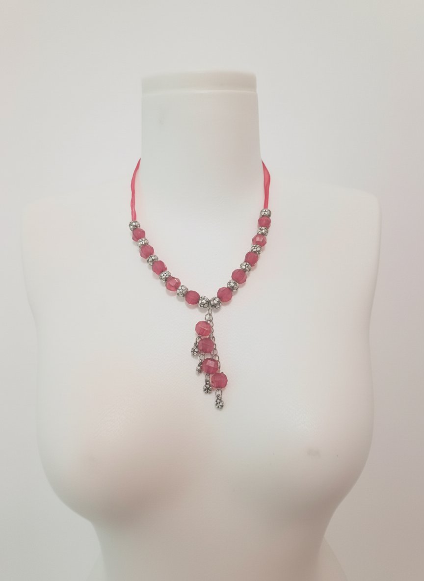 Collier fantaisie composé de perles roses et d'éléments argentés en forme de pampille.