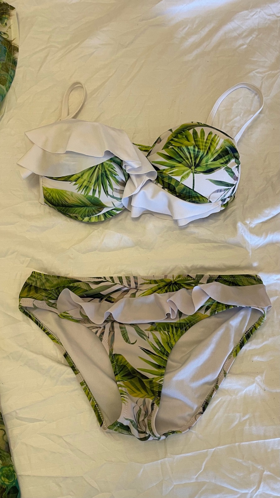 Tenue de plage se compose d'un paréo léger en mousseline et d'un bikini assorti, tous deux arborant un motif floral tropical dans des tons de vert, bleu et blanc