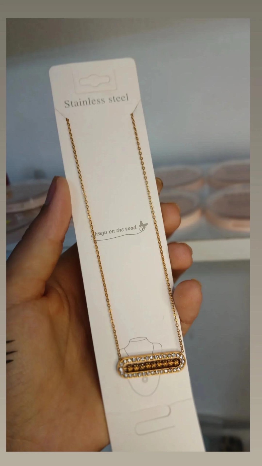 Collier en acier inoxydable doré de style "Messika" présente un pendentif rectangulaire orné de strass.