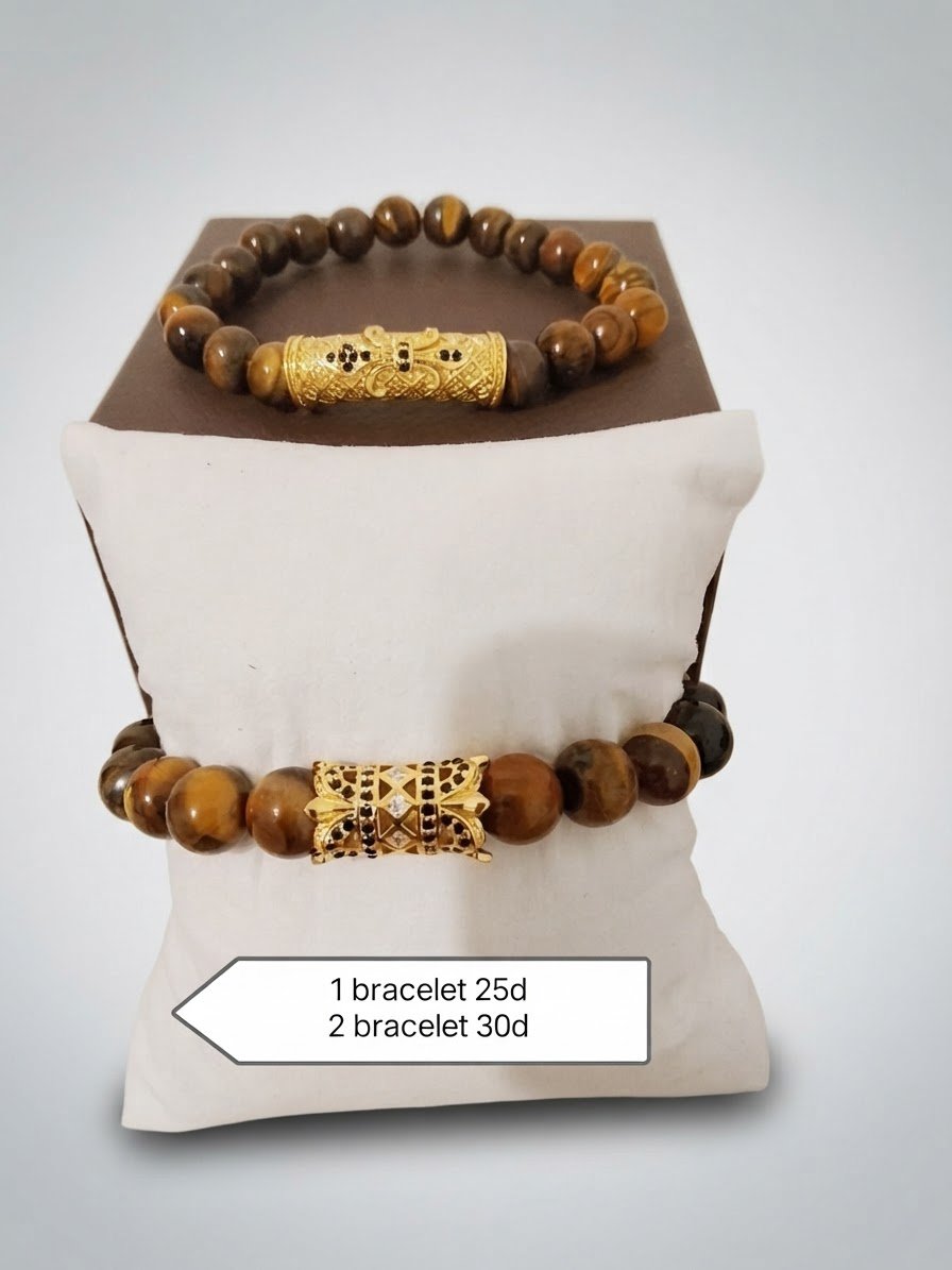 Bracelets en perles d'œil de tigre sont ornés d'inserts cylindriques et décoratifs de couleur dorée. L'image indique une tarification de 25 dinars pour un bracelet et de 30 dinars pour deux bracelets.