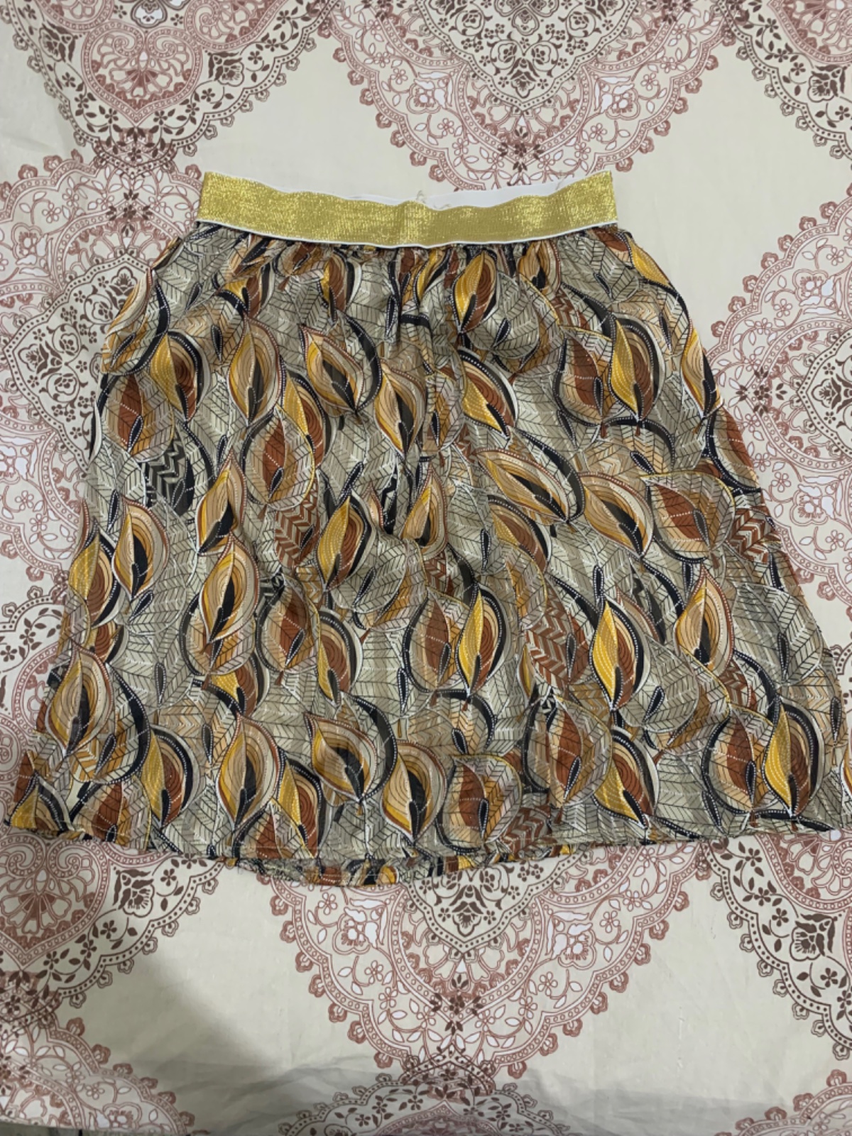 Jupe courte plissée à motif feuilles et taille dorée