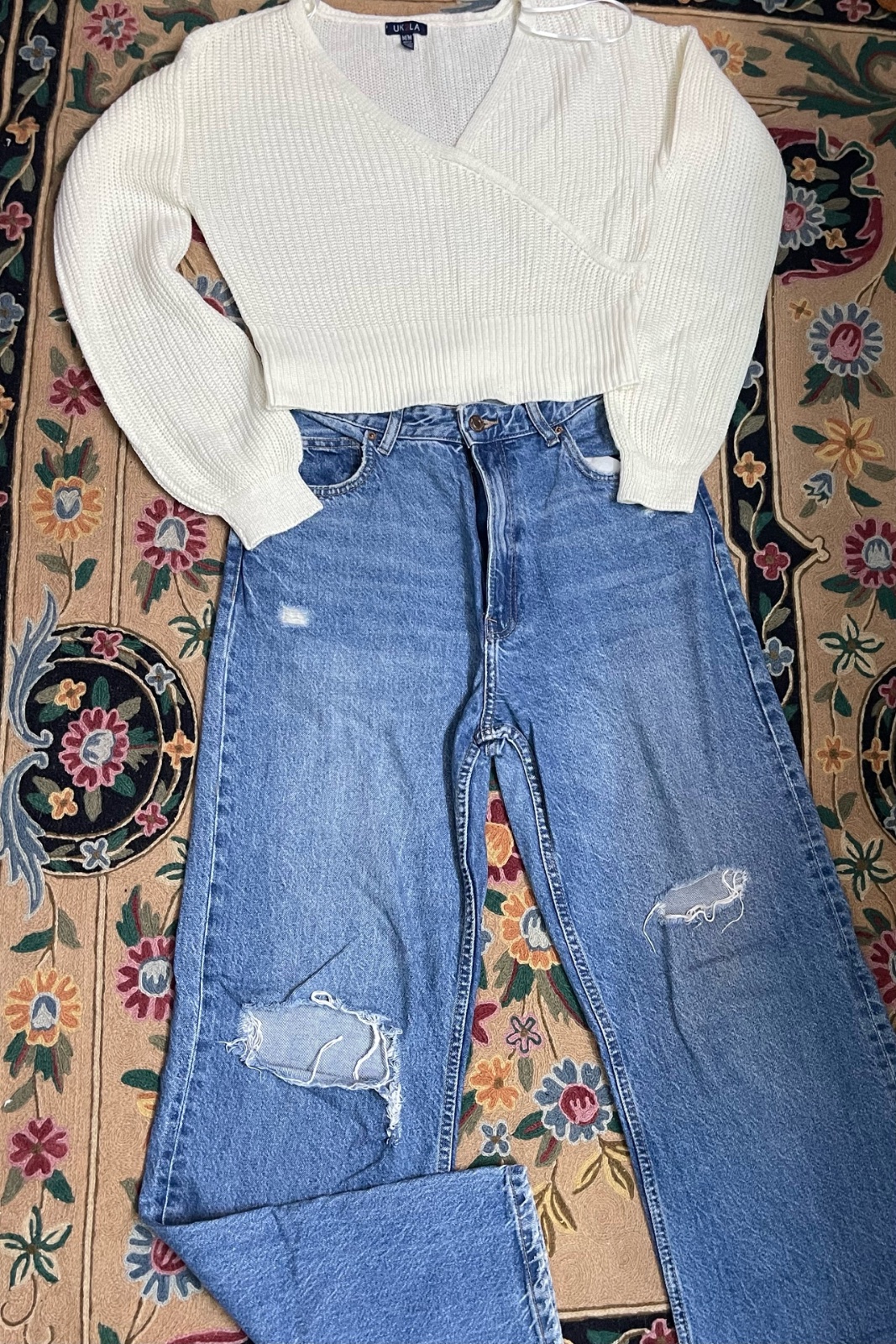 Pantalon en jean Bershka déchiré, associé à un pull beige.